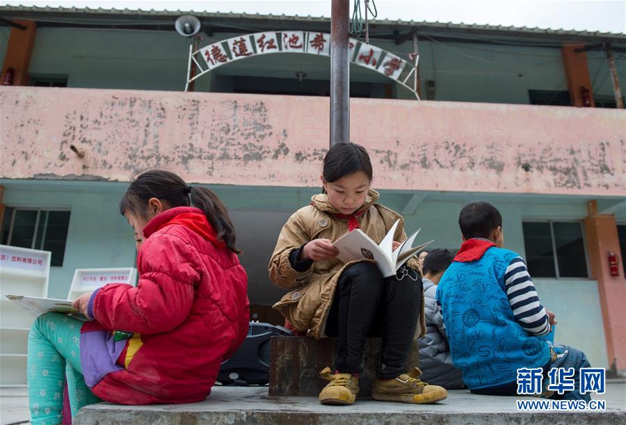 课间休息期间，红池坝小学的孩子们拿着志愿者们捐赠的新书坐在旗杆下阅读（11月20日摄）。新华社记者刘潺摄